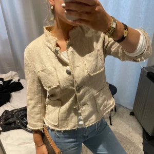 Beige kavaj med knappar - Säljer en stilren beige kavaj/jeansjacka med trekvartsärm och knappar framtill. Kavajen har en fransig kant och två fickor på bröstet. Perfekt för en chic look!🤎🤎 perfekt till våren 
