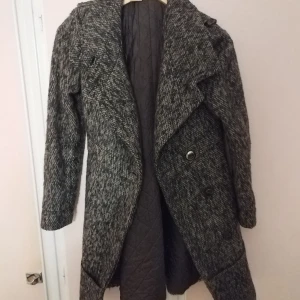 Grå kappa med knappar - Winterjack-women "Mango Pepper Suit Blazer". Snygg grå kappa med ett klassiskt snitt och stora knappar framtill. Den har en elegant krage och är perfekt för kyligare dagar. Kappan är långärmad och har en stilren design som passar till många olika tillfällen. Wool mix fabric. Speckled jacquard. Suit style. Straight design. Lapel-collar V-neck collar. Long sleeve with buttoned cuffs. Shoulder pad. Button fastening on the front. Welt pocket on the chest. Two front flap pockets. Inner lining. Co-ord