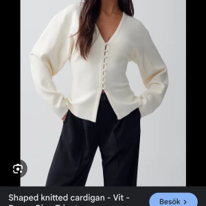 Vit stickad kofta/cardigan Gina Tricot - Snygg beige stickad kofta med knappar framtill. Den har en v-ringad design och långa ärmar, perfekt för en stilren look. Oanvänd med prislapp kvar!