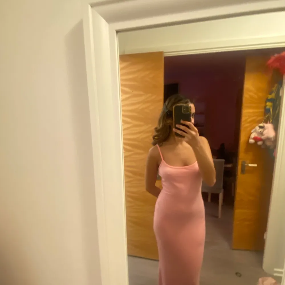 Säljer en elegant rosa långklänning med smala axelband. Klänningen har en figurnära passform som framhäver silhuetten. Perfekt för speciella tillfällen.. Mekot.