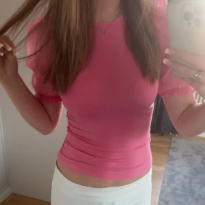 Rosa tight topp - Säljer en söt rosa topp med korta ärmar och volangdetaljer vid ärmslut. Toppen har en tight passform och är perfekt för sommarens varma dagar. Passar bra till både jeans och kjol. Hör av dig vid intresse! 💖