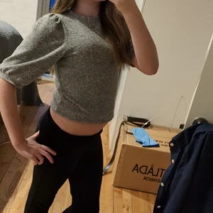 Grå croppad tröja - Säljer en stilren grå croppad tröja med puffiga trekvartsärmar. Perfekt för en trendig look. Passar bra till både jeans och kjol.