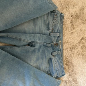 Ljusblå lowwaist jeans  - Säljer ett par ljusblå jeans från Pepe Jeans med klassisk femficksdesign och knappgylf.  De har snygga detaljer på bakfickorna och en läderpatch med logotyp baktill.