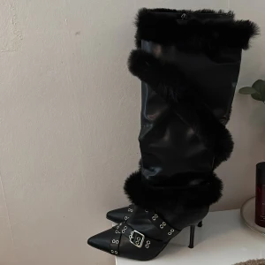 Svarta stövlar med pälsdetaljer - Snygga svarta stövlar med hög klack och spetsig tå. De har pälsdetaljer och dekorativa spännen. har bara använt de vid ett tillfälle. pris går att diskutera vid snabb affär 💕