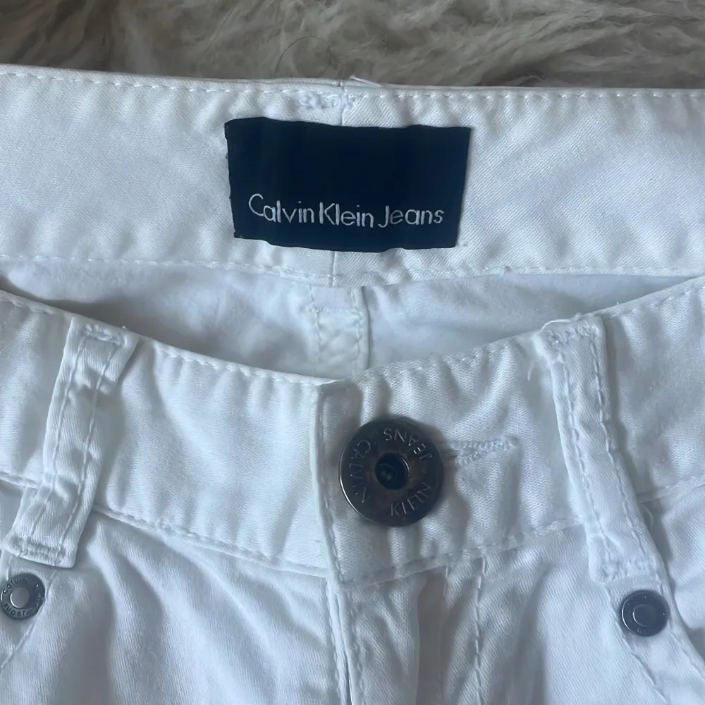 Snygga vita jeans från Calvin Klein med klassisk femficksdesign och knappgylf. Perfekta för en stilren look. De har en rak passform och är tillverkade i ett bekvämt material. Midjemått 80 cm, Innebensmått 73 cm.. Farkut & Housut.