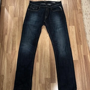 Mörkblå jeans från Replay - Snygga mörkblå jeans från Replay med slitna detaljer och klassisk femficksdesign. De har en dragkedja och knappstängning samt kontrastsömmar som ger en cool look. Perfekta för en avslappnad stil. Storlek 32/34 aldrig använda 