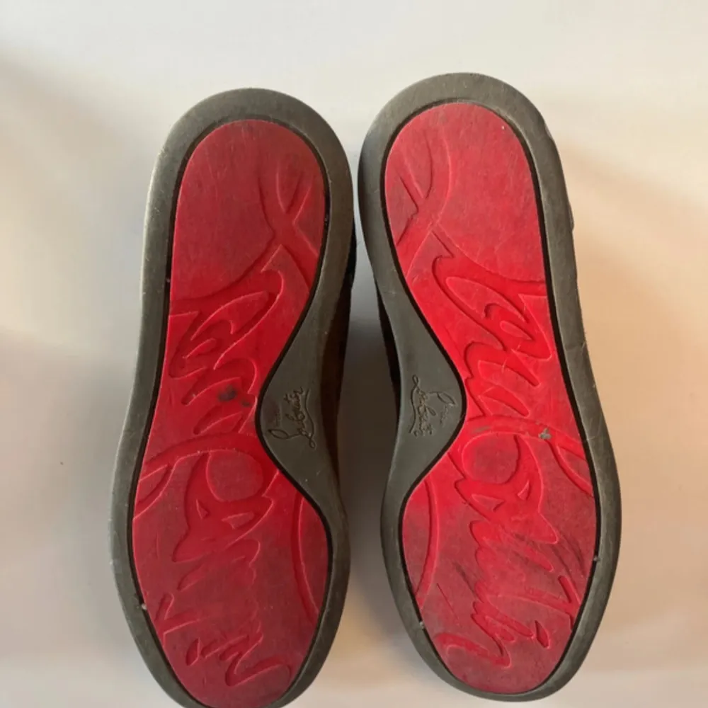 Snygga grå sneakers från Christian Louboutin med den ikoniska röda sulan. Skorna har snörning och är tillverkade i mocka, vilket ger en lyxig känsla. Perfekta för dig som vill ha en stilren och exklusiv look.. Kengät.