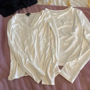 Vita långärmad toppar   - Säljer en vit långärmad topp från H&M i storlek S. Toppen har en v-ringad design och är tillverkad av mjuk polyester och spandex för en bekväm passform. Perfekt för en stilren look.Även en v-ringad créme vit från Amisu. Paketpris 