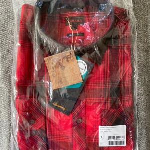 Röd rutig skjorta från Härkila - Snygg röd rutig skjorta från Härkila med klassisk krage och knappar framtill. Fantastisk kvalitet!Skjortan är långärmad och har en tidlös design som passar till många tillfällen.