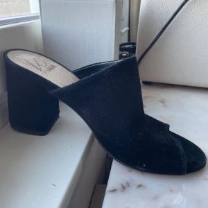 Svarta klackskor från KC COBLER - Snygga svarta klackskor från KC COBLER i mocka. De har en öppen tå och en bred klack som ger stabilitet. Perfekta för en stilren look.