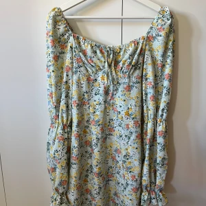 Blommig  klänning -  blommig klänning med långa ärmar. Dragkedja i ryggen, och snörning fram till där du kan justera storleken