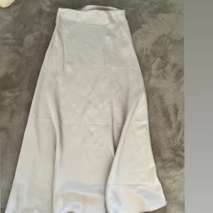 Kräm beige långkjol i satin - Elegant kräm beige långkjol i satin som ger en lyxig känsla. Perfekt för speciella tillfällen med sitt mjuka och glänsande material. Knappt använd och i väldigt nytta skick.🤍Storlek: M,S