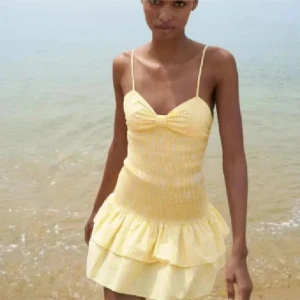 Gul rutig volangklänning med knyt i ryggen - Söt gul kortklänning med smala axelband, volangkjol och rutigt mönster. Klänningen har omlottknytning i ryggen och en feminin v-ringning framtill. Perfekt för varma sommardagar på stranden. DEN ÄR I STORLEK M MEN SITTER SOM XS/S, den är i nyskick!