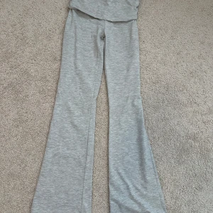 Grå mjukisbyxor från Gina Tricot - Grå mjukisbyxor från Gina Tricot med utsvängda ben. Byxorna har en mjuk och stretchig känsla, perfekt för en avslappnad stil. Passar dig som gillar bekväma och trendiga plagg.