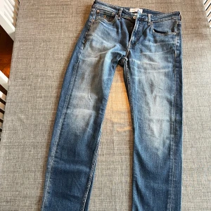 Blå jeans från Calvin Klein - Säljer ett par klassiska blå jeans från Calvin Klein med fem fickor och diskret CK-logo på myntfickan. Jeansen har normal passform och raka ben, samt snygga slitningar framtill för en avslappnad look. Slim taper. Knappt använda i jättefint skick.