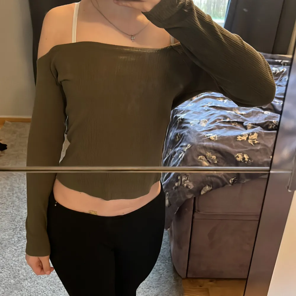 Säljer en olivgrön ribbad offshoulder topp med långa ärmar. Toppen är croppad och har en tight passform, perfekt för att skapa en trendig look.. Yläosat.
