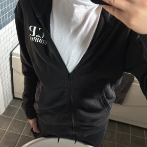 Svart hoodie med dragkedja från C.P. Company - Svart hoodie med dragkedja och huva från C.P. Company. Jackan har vita logotypdetaljer på bröstet och karakteristiska glasögon på huvan. Perfekt för en avslappnad streetwear-look. Säljer den pågrund av den är för liten skulle säga att den passar 170 storlek. Ny pris 2200 och jag säljer för 1100