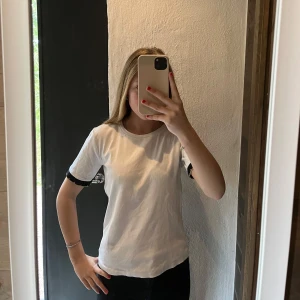 Vit t-shirt med svarta detaljer från Zara - Vit t-shirt från Zara med svarta ribbade detaljer på ärmsluten. Klassisk rund halsringning och normal passform. Är i stolek M men jag har vanligt vis xs/s och den sitter bra passar nog M också eftersom den är stretchig..🥰🫰🏼den har en lite fleck den syns dock inte tydligt, det är nog en smink fleck… vid halsen