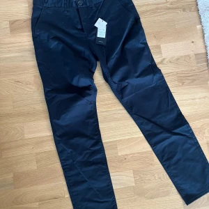 Mörkblå chinos från Matinique - Säljer ett par stilrena mörkblå chinos från Matinique. Byxorna har normal passform, knapp och dragkedja i gylfen samt bälteshällor. Perfekta för dig som vill ha en klassisk look med snygga detaljer.