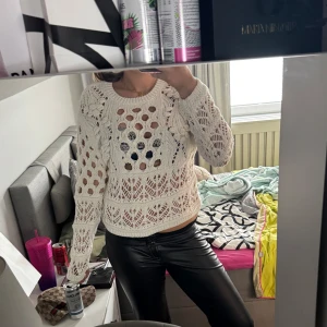 Vit virkad tröja med hålmönster - Säljer en vit virkad tröja med hålmönster och rund hals. Tröjan har lång ärm och är perfekt för lager-på-lager. Snygg detalj med olika virkade mönster och lätt transparent känsla.