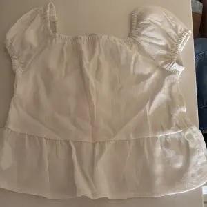 Söt vit blus från H&M med korta puffärmar och volang nertill. Blusen har en lätt rynkad struktur och är tillverkad i ett tunt, luftigt material. Perfekt för varma dagar och enkel att matcha med jeans eller kjol.