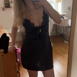 Svart kort klänning med spets och knyt - Säljer en svart kort klänning med smala axelband, djup v-ringning med spetskant och knyt framtill från ASOS pga att den inte kommer till användning💕💕storlek 38. Skriv vid frågor☺️Pris kan diskuteras 