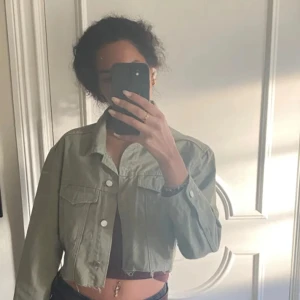 Grön croppad jacka - Snygg grön croppad jacka med långa ärmar och knappar framtill. Perfekt för en avslappnad stil och passar bra till jeans. Jackan har en klassisk krage och två bröstfickor.  Aldrig använt, kontakta vid frågor 