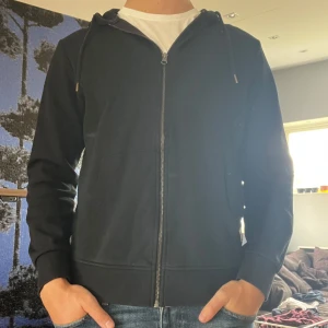 Svart Hoodie Jack & Jones - Säljer en svart hoodie från Jack & Jones i mkt bra skick. Kommer inte till användning längre. Normal i storlek. Säljer även en vinröd exakt likadan där paketpris kan lösas vid köp av båda!🍾👍🏼