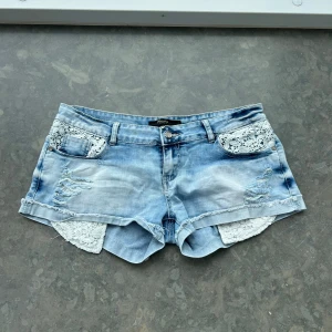 Jeansshorts  - Så himla sbygga jeansshorts med coola detalijer. Spets och slitningar . Har tyvärr ingen bild på. Midjemått: ca 44 cm Midjehöjd ca 20 cm. Svårt att uppskatta storlek men kolla måtten.💕 finns en super liten fläck som säkert går att tvätta bort. 
