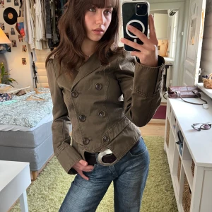 Olivgrön kavajjacka från Patrizia Pepe - Olivgrön italiensk vintage kavajjacka från Patrizia Pepe med dubbelknäppning. Jackan har långa ärmar, axeldetaljer och är tillverkad i bomull. Snygg och figurnära modell. I storlek 44 men passar mig som har storlek XS om man knäpper knapparna längst ut!  