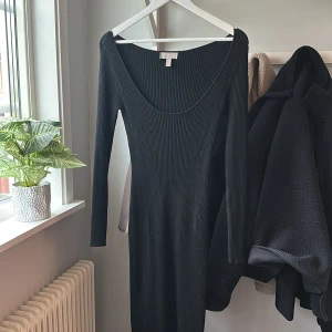 Svart ribbad långklänning från H&M - Säljer en svart ribbad långklänning från H&M med lång ärm och djup rundad ringning. Klänningen har en tight passform och är perfekt för dig som gillar en stilren och enkel look. Är i mycket fint skick knappt använd ❤️
