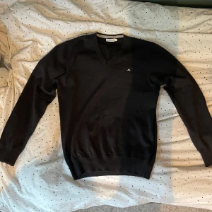 Svart v-ringad tröja från J.Lindeberg - Säljer en stilren svart v-ringad tröja från J.Lindeberg. Tröjan har en liten broderad logga på bröstet och är tillverkad i ett mjukt material. Perfekt för dig som gillar klassisk och enkel stil. Perfekt skick. Det står M men de passar S. Därför jag säljer den för den var för liten