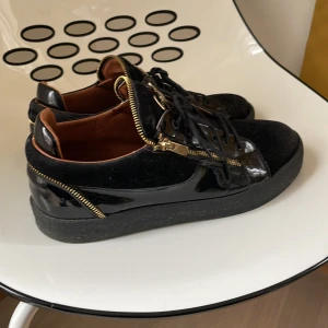 Svarta sneakers med gulddragkedjor från Giuseppe Zanotti - Säljer ett par svarta sneakers från Giuseppe Zanotti då dem inte passar mig längre. Ny pris ungefär 6500kr säljer för 1500kr.