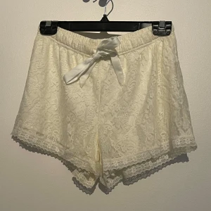 vita spets-shorts med rosett - vita shorts med spets, rosett framtill och elastisk midja. perfekta för sommaren eller som pyjamas shorts. endast använda ett fåtal gånger. kommer från ett djur och rökfritt hem 🖤