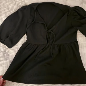 Svart blus med knytning - Blus med knytning framtill och lätt puffade ärmar. Blusen har en lös passform och är tillverkad i ett mjukt, lätt material.🖤