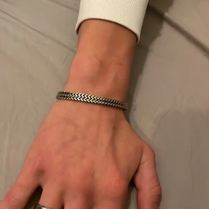 Armband - Stilrent armband i silverfärg med tydligt fiskbensmönster och robust lås. Passar perfekt som accessoar för en modern look. Enkel att matcha med andra smycken. Av märket Arock. 600kr nytt.