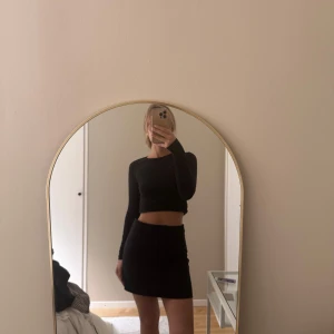 Svart kortkjol - Enkel och stilren svart kortkjol med rak passform. Kjolen är midjehög och har en klassisk look som passar till många olika outfits. Perfekt för dig som gillar minimalistisk stil.