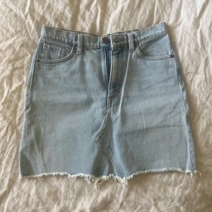Ljusblå jeanskjol från Monki  - Säljer en ljusblå jeanskjol från Monki i klassisk femficksmodell. Kjolen har rå, fransig nederkant och normal passform. Perfekt till sommaren och enkel att styla med olika toppar. Står stlk 36 men ganska tajt så snarare 34 - XS/S.