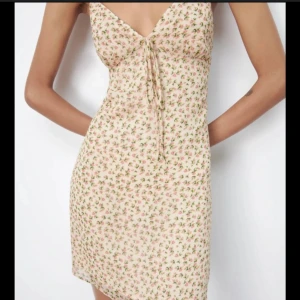 Blommig klänning - Supersöt kortklänning med små rosa blommor. Klänningen har smala axelband, v-ringning och knytdetalj framtill. Den har även djup rygg som man knyter. Materialet känns lätt och somrigt, perfekt för varma dagar eller midsommar! Den är i L men passar mig som är s/m. 