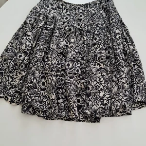 Svartvit blommig kjol från Strenesse Blue i Siden. - Säljer en svartvit kjol från Strenesse Blue med blommigt mönster. Kjolen är tillverkad i 100% silke och har en luftig och lätt känsla. Perfekt för dig som gillar unika mönster och vill ha något som sticker ut.