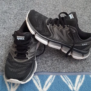 Svarta New Balance Rubix sneakers - Snygga svarta New Balance Rubix sneakers med grå detaljer och vit sula. Ovandelen är i mesh för bra andningsförmåga och skorna har klassisk snörning. Perfekta för dig som gillar sportig stil och vill ha bekväma skor till träning eller vardag. Skor är är mycket lätta och bekväma i mycket bra skick. 