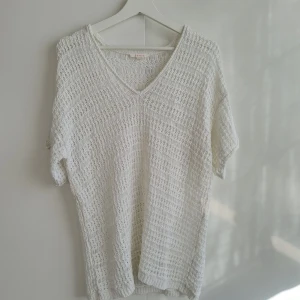 Vit virkad topp Esprit - Säljer en vit virkad topp från Esprit med v-ringning och korta ärmar. Toppen har ett luftigt och mönstrat virkat material som passar perfekt till varmare dagar. Enkel och stilren design som är lätt att matcha.