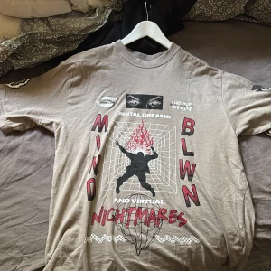 Beige t-shirt med tryck från Junkyard - Cool beige t-shirt från Junkyard med stort grafiskt tryck på framsidan och texten 'Mind Blwn' och 'Nightmares'. T-shirten har rund hals och korta ärmar, perfekt för en avslappnad streetwear-look.