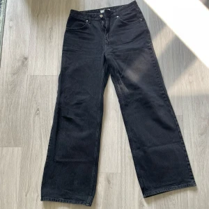 Svarta wide jeans från Pull&Bear - Säljer ett par svarta jeans från Pull&Bear med hög midja och breda ben. Klassisk femficksmodell med dragkedja och knapp framtill. Jeansen är i denim och har en snygg, mörk tvätt som passar till allt.