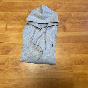 Grå hoodie från Polo Ralph Lauren - Säljer en stilren grå hoodie från Polo Ralph Lauren med klassisk huva och dragsko. Storleken är slim fitt xl vilket är ungefär M