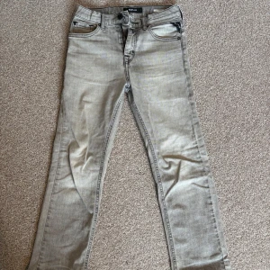 Replay ljusgrå jeans Thad - Säljer ett par ljusgrå jeans från Replay, modell Thad. Jeansen har klassisk femficksdesign, raka ben och snygga detaljer på bakfickorna. Tillverkade i mjukt denimtyg med dragkedjegylf och Replay-logga på bakfickan.