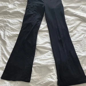 Svarta bootcut leggings med vikt midja - Säljer ett par svarta leggings med bootcut-ben och en bred, vikt midja. De är stretchiga och sitter skönt, perfekta till vardags eller när du vill ha en avslappnad look.