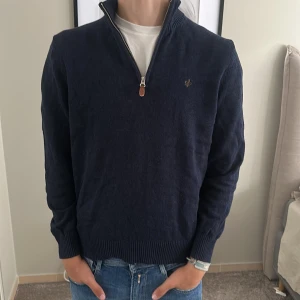 Marinblå half zip tröja från Morris - Snygg marinblå tröja från Morris med half zip och liten broderad logga på bröstet. Tröjan har ribbade muddar och krage, lång ärm och är gjord i mjuk bomull. Perfekt till jeans och funkar året runt.