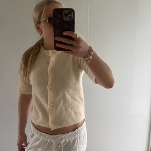 Gul stickad blus från Gina Tricot - Superfin gul stickad blus från Gina Tricot med korta ärmar och pärlknappar framtill. Modellen är croppad och har en mjuk, mysig känsla. Perfekt att styla med jeans eller kjol för en chill look.