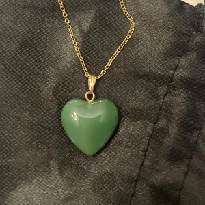 Grönt hjärta halsband glashjärta  - Sött halsband med en berlock av ett grönt glashjärta. Kedjan är i guldimitation och justerbar 40-45 cm. 